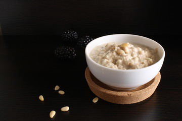 Oat porridge with blackberries, ears of corn on a dark background