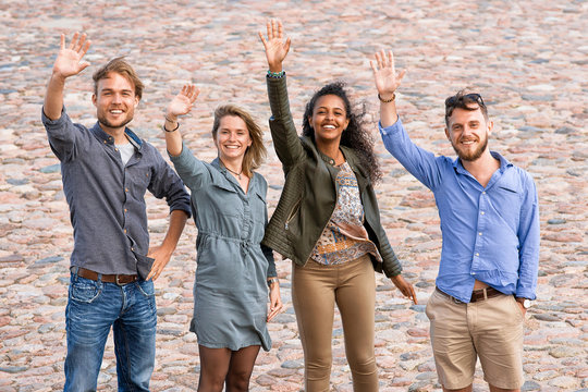 Group of four young multiracial diversity friends waving their hands