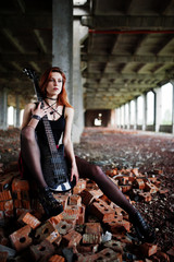 Red haired punk girl wear on black and red skirt, with bass guitar at abadoned place. Portrait of...