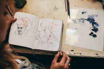 Female artist looking at sketches in her studio - Powered by Adobe