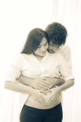 Man holding pregnant  woman belly with carefully, people with family concept. vintage tone.