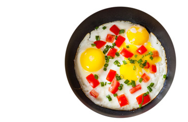 fried eggs with vegetables in a frying pan. top view. isolated on white