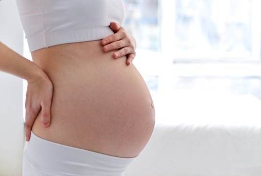pregnant woman caressing her belly over white background