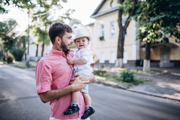 Happy father and son walk in old city street. City road with old bulding and green trees on the background.