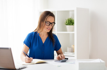 woman with calculator and notebook at office