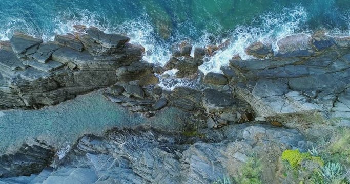 aerial overhead view of ocean mediterranean sea waves reaching and crashing on rocky shore beach coast. Sunny weather. 4k slow motion 60p top view drone video shot