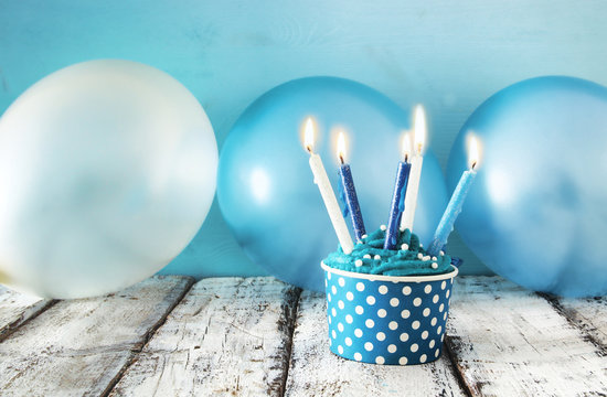 Birthday concept with cupcake and candles on wooden table.