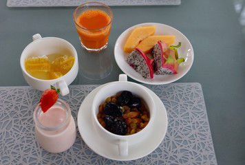 Healthy breakfast, nutrition concept: yogurt , fruits, nuts, fresh carrot juice, coffee. Balanced diet