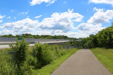 The walkway in the park next to the highway.
