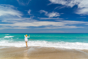 Fototapeta na wymiar Young woman standing on a beach and enjoying the sun