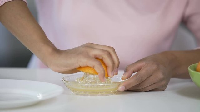 Woman Juicing Out Orange With Handheld Juicer, Taking Care Of Health, Nutrition