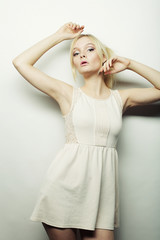 Naklejka premium fashion blond woman in white dress posing in studio