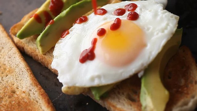 Avocado toast with a fried egg and hot chili sauce