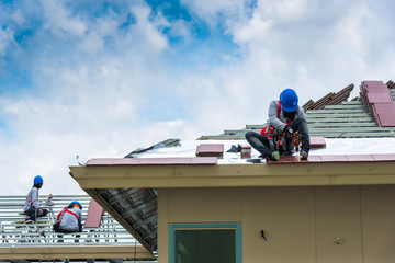 Workers are drilling roof tiles with a drill.