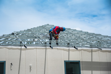 Workers are building a steel roof frame on high. 