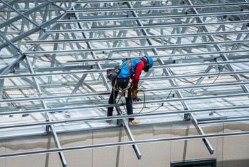 Workers are building a steel roof frame on high. 