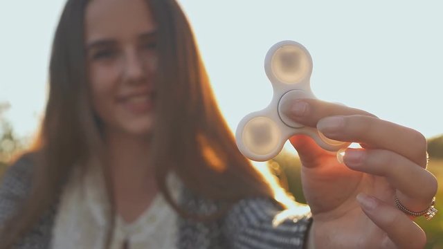 Young girl holding a white fidget spinners outdoors.