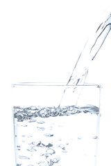 Pouring drinking water into glass on white background.