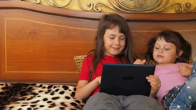 Sisters with a tablet at home. Two little girls with a tablet.
