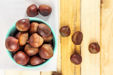Chestnuts in bucket, on rustic textures with copyspace