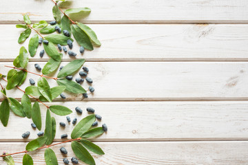 Ripe berries of a honeysuckle on a wooden background. Summer harvest.