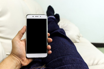 closeup hand holding smartphone in living room with soft-focus in the background, over light