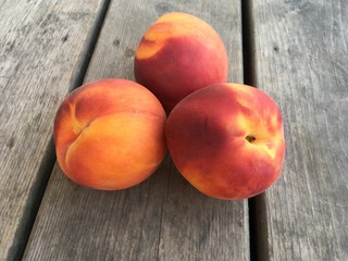 a cluster of fresh peaches on a wooden table top