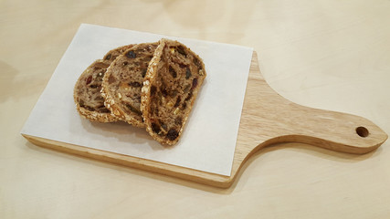 whole wheat fruit bread with raisin nut and grain on wooden chopping block / whole wheat fruit bread
