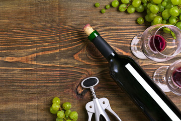 Red wine bottle, grape, chocolate and glasses over wooden table. Top view with copy space