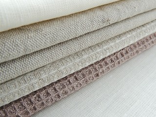 Handmade sewing linen cotton napkins, kitchen towels on white linen background. Different colours. Food photo props.