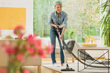 Woman is vacuuming beige carpet