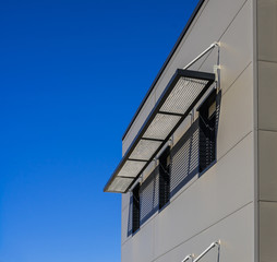 Moderne Fassade aus Blech und Fenster mit Gitterrost zum Sonnenschutz im Außenraum - Modern...