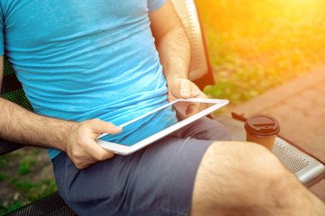 Man sitting on a bench and using a digital tablet