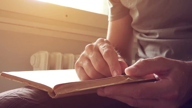 Reader with an old vintage book, close up of male hands holding weathered novel with yellow pages