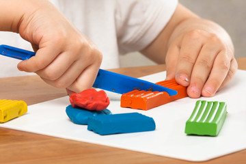 hands of child cutting plasticine with a plastic knife