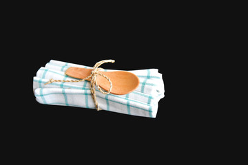 Small Wooden Spoon Tied on a White and Blue Napkin Isolated on Black Background
