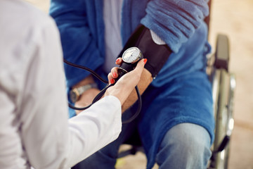 close up checking the hypertension assessment of blood pressure elderly man .