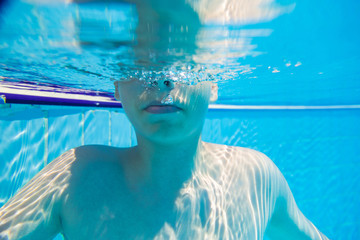 Teenage boy, enjoying of life at spa resort swimming pool. Split level of water.