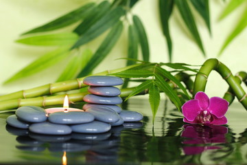 Obraz na płótnie Canvas Galets gris disposés en mode de vie zen avec des tiges de bambou ,une orchidée et une bougie allumée