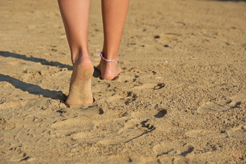 girl's legs walking on a sandy beach