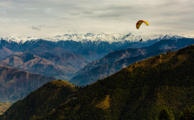 Para Gliding adventure at beautiful valley of Khajjiar, Himachal Pradesh, India. Himalayan Mountains in the background.