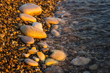 sea pebble beach with multicoloured stones, waves with foam