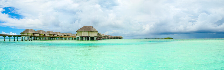 Fototapeta premium Panoramic landscape of Maldives beach with overwater bungalow