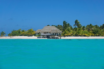Coastline with a tropical beach house and the turquoise water of the inner lagoon of the atoll of Tikehau, Tuamotus archipelago, French Polynesia, south Pacific ocean