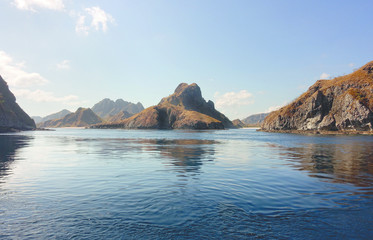 Coastline of mountains with green vegetation reflected  in blue ocean water at Labuan Bajo in Flores, Indonesia.