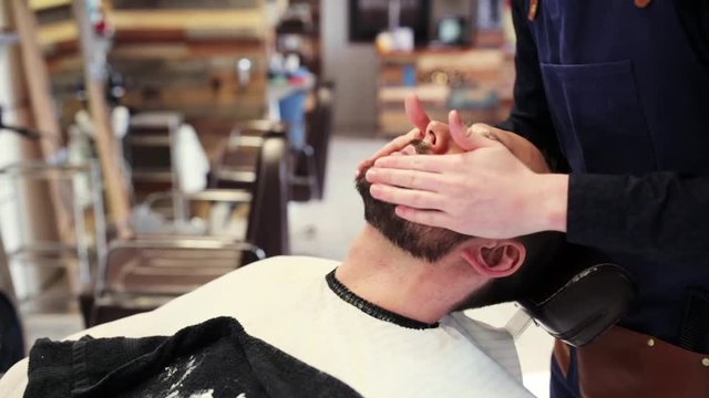 barber applying beard styler to male face