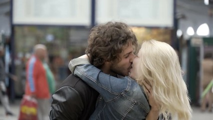 Reunited couple with young girl running to meet boyfriend kissing and hugging for reunion in airport train station - Powered by Adobe