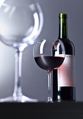 Bottle and glass of red wine .
