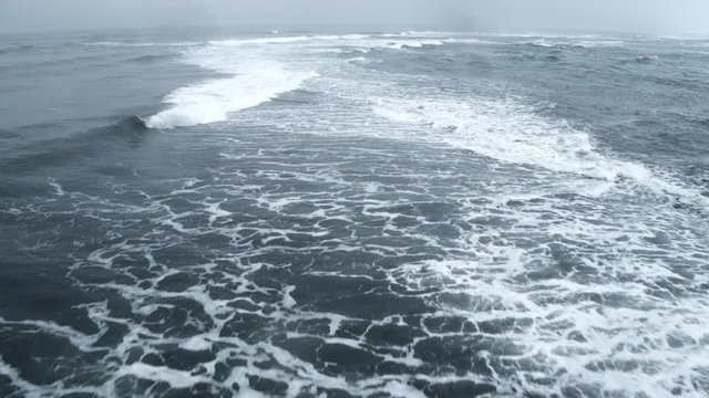 Aerial shot, waves crash in icy waters