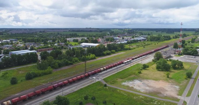 Oil and gas, transport by train. Beautiful summer nature and cargo train, runs through the city. Aerial footage.